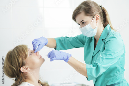 A nurse wearing a medical mask takes a swab from a patient s nose.