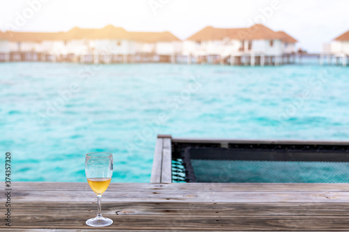 Glasses of sparkling wine on vacation. Glass of white wine in the sunset overlooking the sea. Glass of wine on the wooden jetty at sunny sea. 