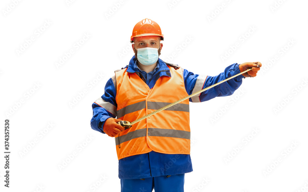 Handsome contractor, builder in face mask isolated over white studio background. Concept of professional occupation, work, job, building, investment. Copyspace for ad, text. Caucasian man wearing Handsome contractor, builder in face mask isolated over white studio background. Concept of professional occupation, work, job, building, investment. Copyspace for ad, text. Caucasian man wearing