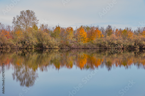 Fototapeta Naklejka Na Ścianę i Meble -  Autumn forest landscape reflection on the waters of small lake at sunset lights of sun
