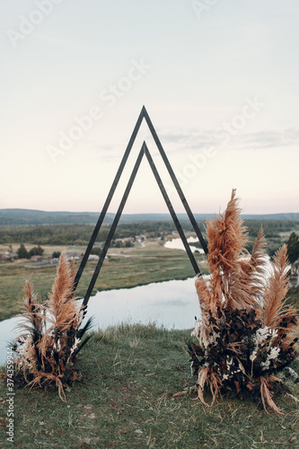 Wedding triangular arch in boho style. Floristics from dried flowers for a wedding, exit ceremony.