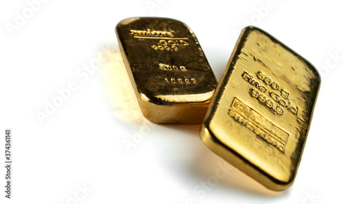 Two cast gold bars isolated on a white background. Selective focus.