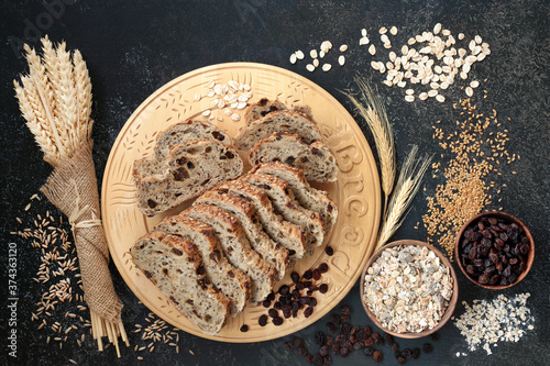 High fibre health food with raisin rye bread loaf, bowls of raisins and muesli, with barley flakes, flax seed and sheaths of grain. High in antioxidants, omega 3, vitamins and protein with low gi. 