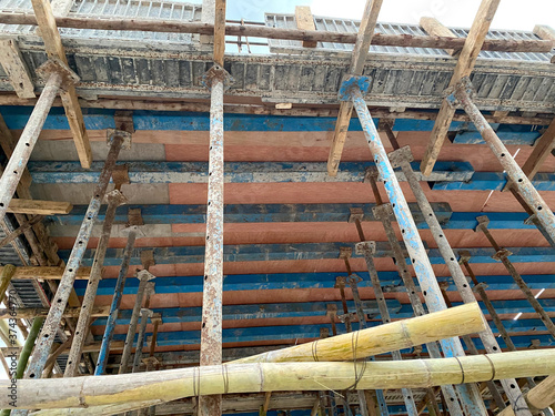 Home construction with wooden scaffolding for building from bottom view under cloudy sky