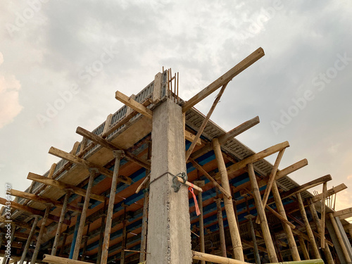 Home construction with wooden scaffolding for building from bottom view under cloudy sky