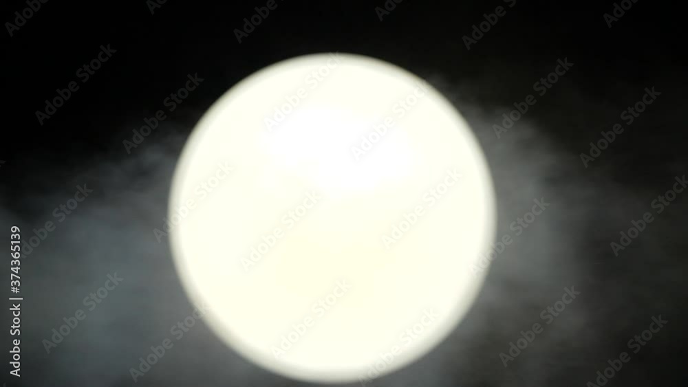 Close-up view of a bright white circle, similar to the moon, which the wind blows in black and white background. Snow-white ball on a dark background. Mystical smoke and fog soars above a bright ball. Close-up view of a bright white circle, similar to the moon, which the wind blows in black and white background. Snow-white ball on a dark background. Mystical smoke and fog soars above a bright ball.