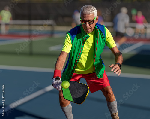 Senior man hitting a pickleball with paddle