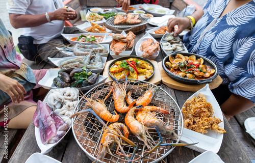 Seafood buffet grill with raw shrimp, shellfish, crab, squid prepared empty, comes in a white plate, looks delicious, delicious, ready to eat, available on a wooden table with a grill.