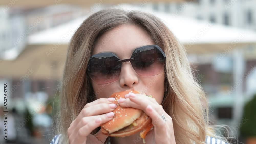 Hungry girl eating hamburger or cheeseburger on street food court hd stock footage