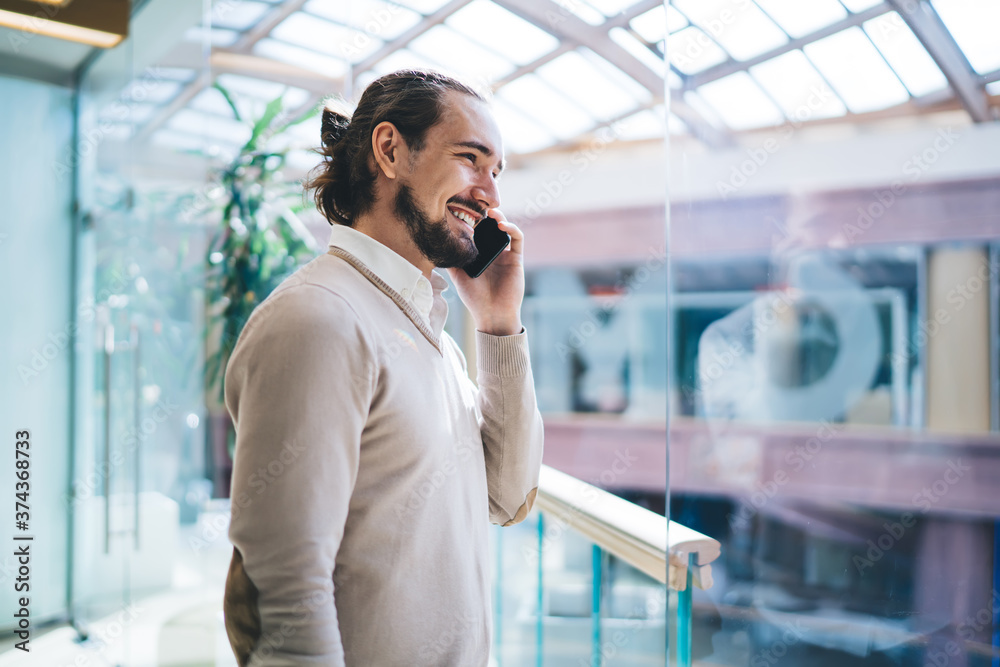 Young man standing in business center and speaking on cellphone with smile Young man standing in business center and speaking on cellphone with smile