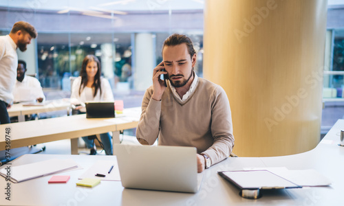 Busy male executive manager having conversation on smartphone in office