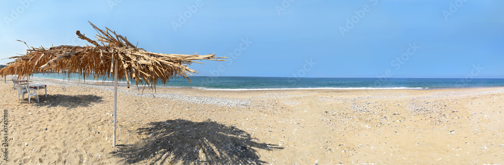 large panoramic  of a empty beach with a straw umbrella