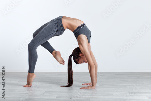 Athletic woman doing fitness exercise on white wall