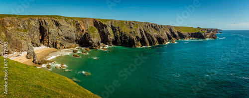A sandy bay surrounded by stacks, stumps and limestone cliffs on the Pembrokeshire coast, Wales near Castlemartin in early summer photo
