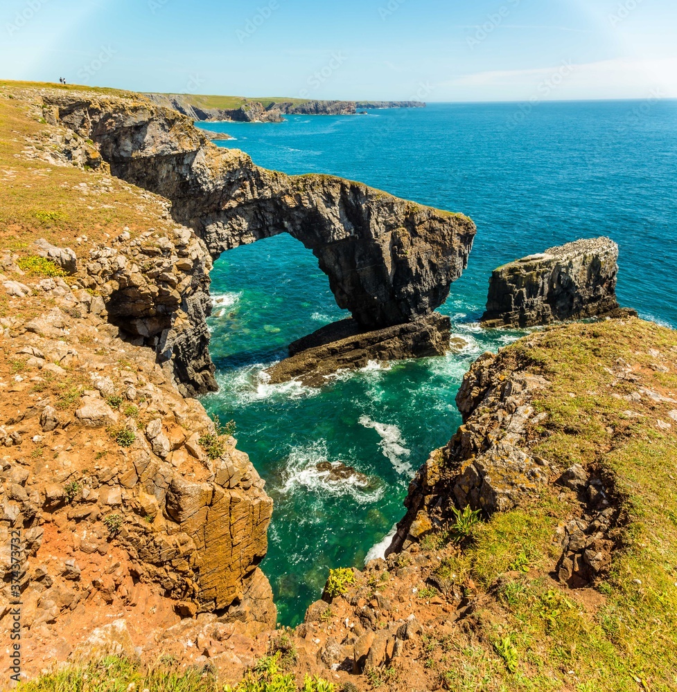 The Green Bridge of Wales framed by a gap in the limestone cliff  on the Pembrokeshire coast, Wales near Castlemartin in early summer