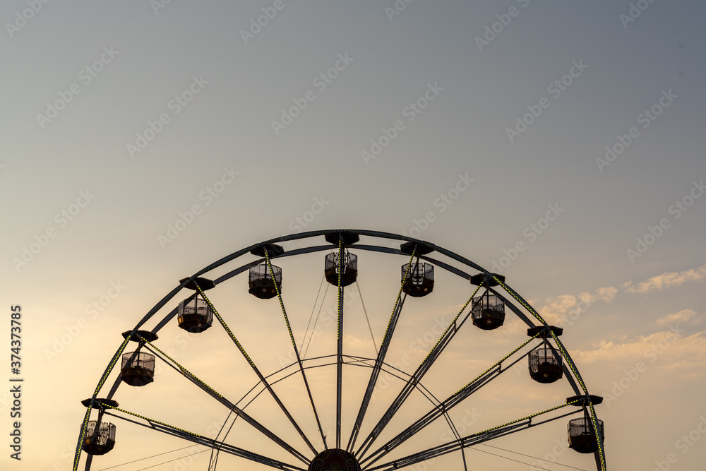 view of a ferris wheel in silhouette at sunset