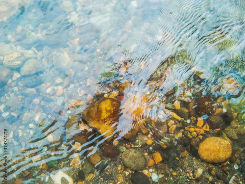 Crystal clear water of river surface with small stones and pebbles.