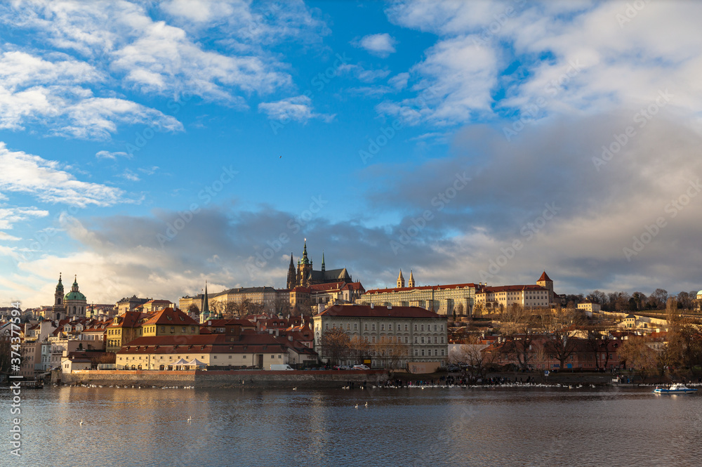 Beautiful view of Mala Strana old district of Prague on the Vltava river side with Wallenstein Palace, Prague Castle and St. Nicholas Church, on sunny winter day with blue sky cloud,  Czech Republic