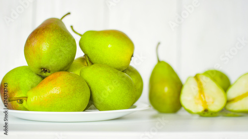 ripe pears in a white plate on a white background close-up. background with pears. green pears on a white background.