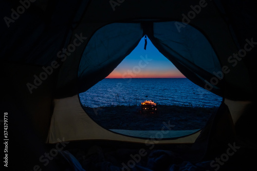 View from a tourist tent on bonfire on the seashore at sunset.