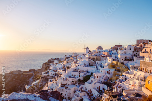 Fototapeta Naklejka Na Ścianę i Meble -  Sunset at the Island Of Santorini Greece, beautiful whitewashed village Oia with church and windmill during sunset, streets of Oia Santorini during summer vacation at the Greek Island