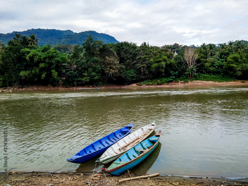 Small boat floating on the riverside with mountain view. Small boat floating on the riverside with mountain view.