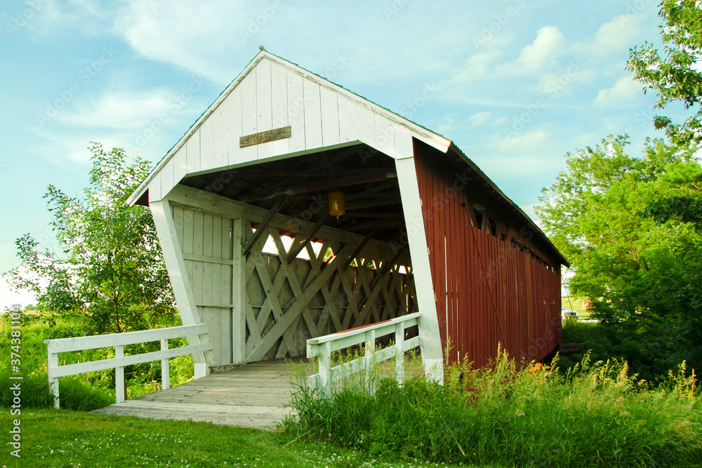 The Imes Covered bridge leaning to the left in Madison County, Iowa, three quarter view with trusses, cross beams, white railing, green trees, blue skies and white clouds Royalty free stock photo The Imes Covered bridge leaning to the left in Madison County, Iowa, three quarter view with trusses, cross beams, white railing, green trees, blue skies and white clouds Royalty free stock photo