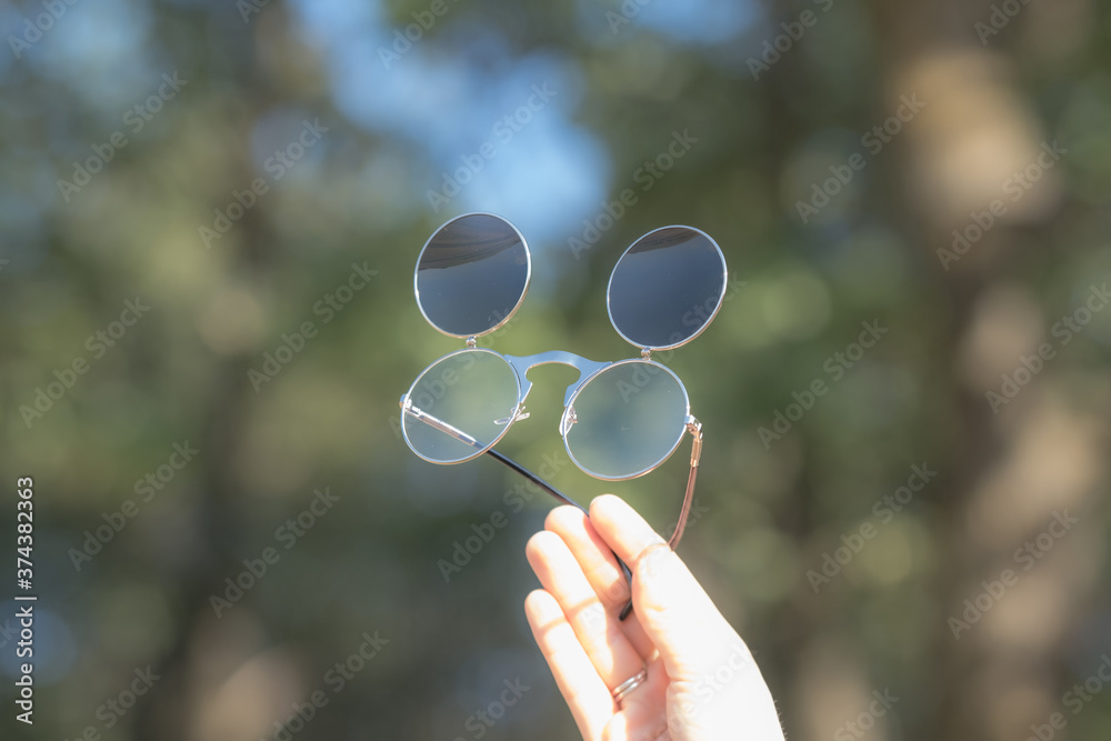 Steampunk sunglasses held in hand with round lenses retro flip up model close up shoot in a summer day. Selective focus Steampunk sunglasses held in hand with round lenses retro flip up model close up shoot in a summer day. Selective focus