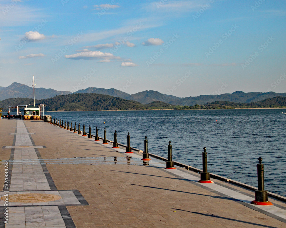 Obraz premium The evening sun sinks slowly in the west, casting shadows from the railings on to an ornamental walkway in a Turkish seaside resort.