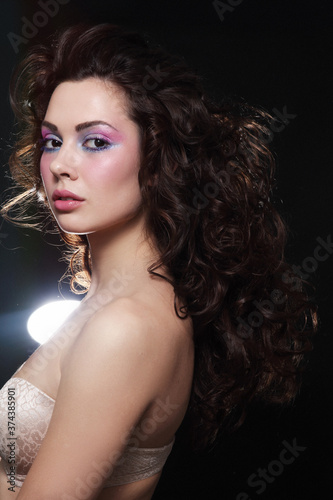 Vintage style portrait of young beautiful woman with long curly hair and fancy disco makeup
