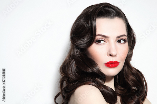 Young beautiful brunette with long curly hair and red lipstick