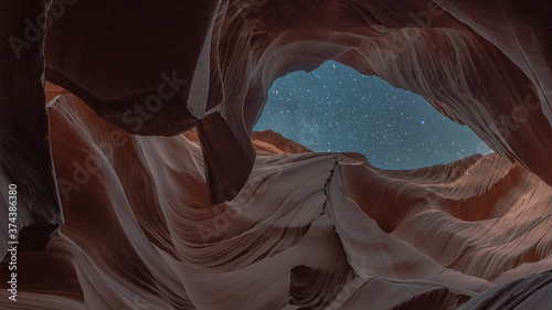 Eagle looking at the colorful Antelope canyon during a clear night with stars in the sky.