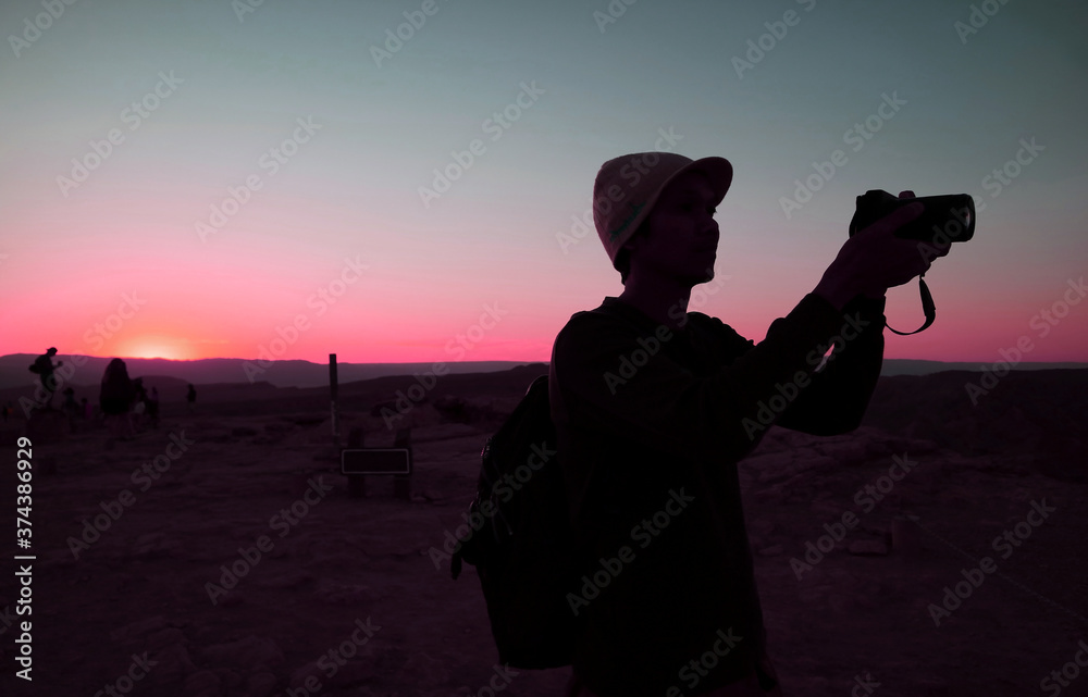 Silhouette of a man taking photo against blue and pink sunset sky