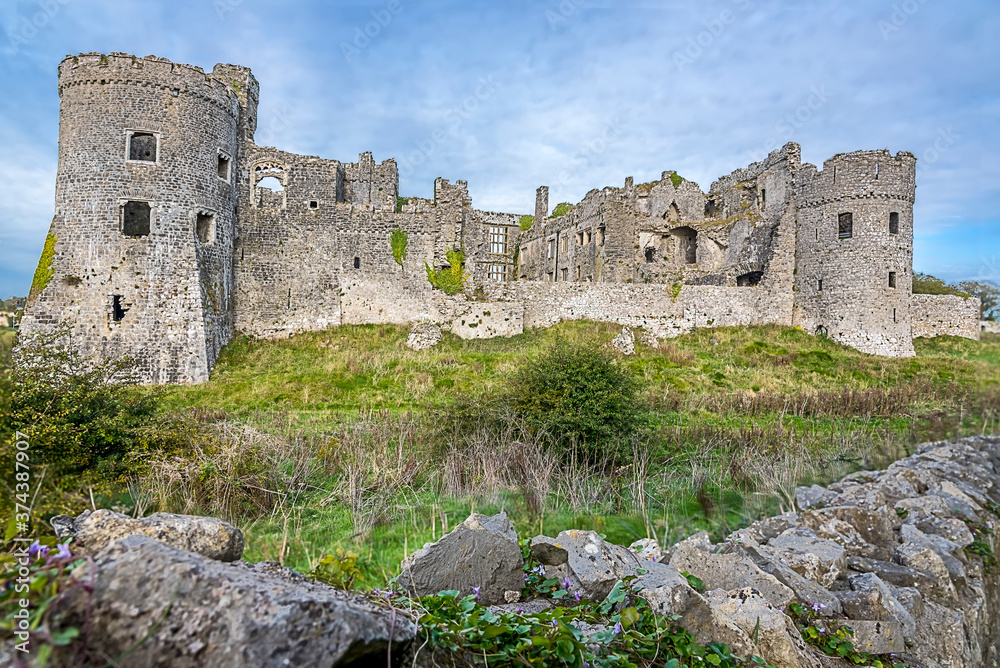 A view across a dry stone wall of the ruins of the old castle at Carew, Pembrokeshire, UK