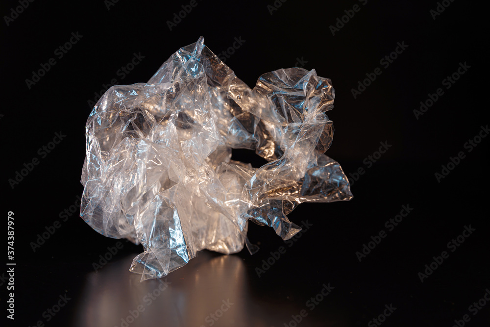 A piece of crumpled polyethylene on a black background. Inorganic waste. Ecology and waste recycling concept. A piece of crumpled polyethylene on a black background. Inorganic waste. Ecology and waste recycling concept.
