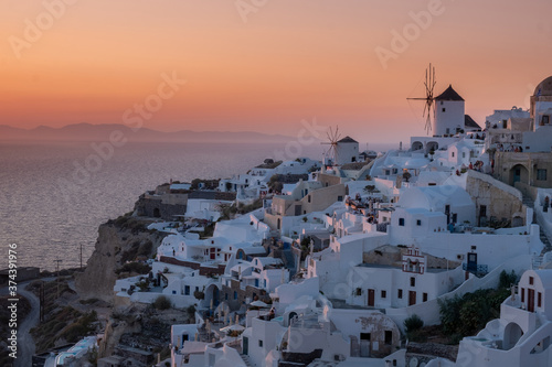 Sunset at the Island Of Santorini Greece, beautiful whitewashed village Oia with church and windmill during sunset, streets of Oia Santorini during summer vacation at the Greek Island photo