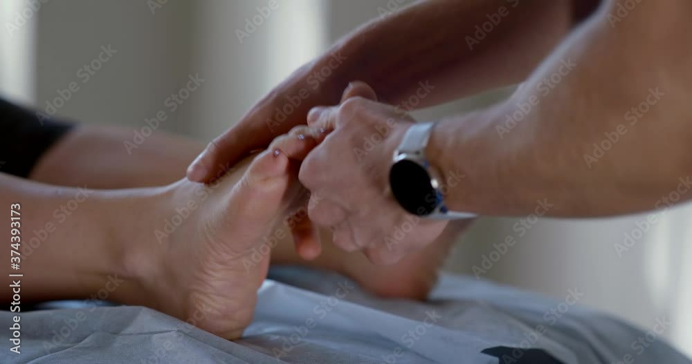 the osteopath twitches the patient's toes and twists the foot with both hands. close up the osteopath twitches the patient's toes and twists the foot with both hands. close up