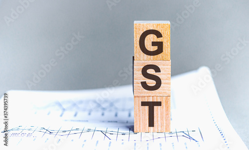 GST word written on wood block. Wooden block with words GST - acronim GST - Goods and Services Tax. photo