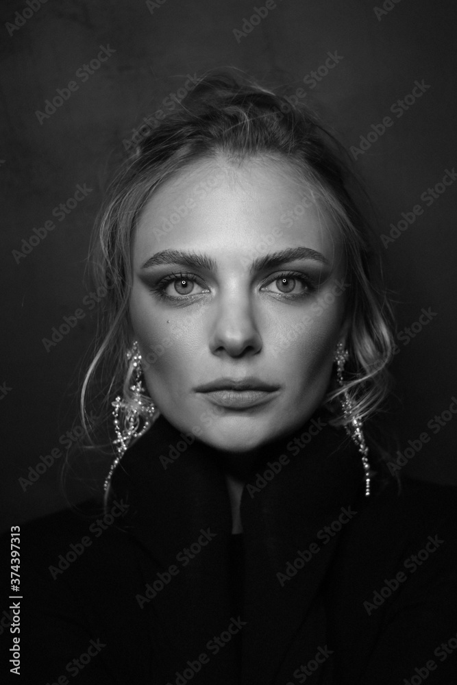 Vintage style black and white portrait of young beautiful woman with blonde hair and fancy earrings