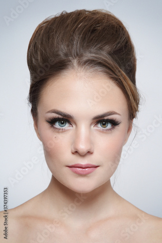 Vintage style portrait of young beautiful woman with fancy hair bun and natural makeup © Olga Ekaterincheva
