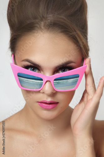 Vintage style portrait of young beautiful woman with fancy sunglasses