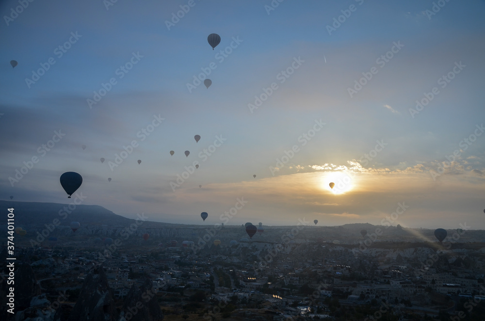 Colorful hot air balloons flying over mountains landscape and the valley at Cappadocia in the sunrise sky at foggy morning
