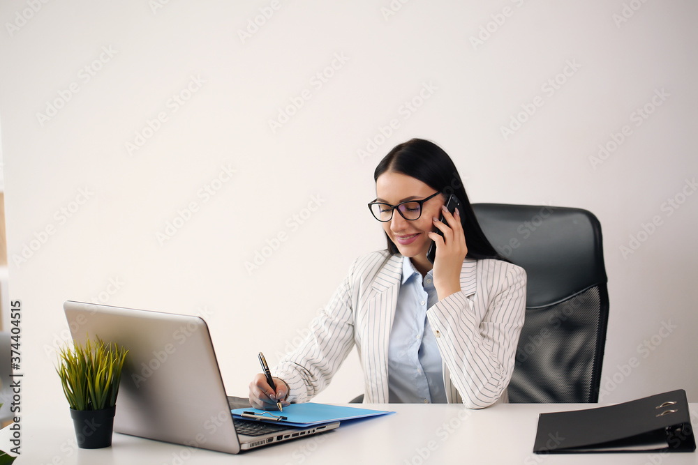 Concentrated young beautiful businesswoman working on laptop in bright modern office Concentrated young beautiful businesswoman working on laptop in bright modern office