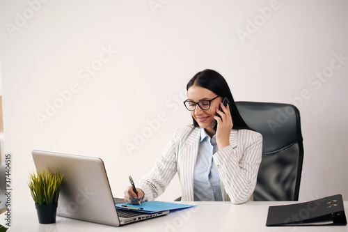 Concentrated young beautiful businesswoman working on laptop in bright modern office © ostap_davydiak