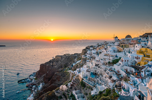 Sunset at the Island Of Santorini Greece, beautiful whitewashed village Oia with church and windmill during sunset, streets of Oia Santorini during summer vacation at the Greek Island photo