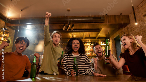 Goal. Happy friends in the bar watching sports match on TV together, drinking beer and celebrating victory. People, leisure, friendship and entertainment concept
