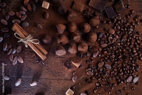 art background with healthy delicious dark truffles, chocolate and ingridients: natural cocoa beans, powder, cacao butter, cane sugar. healthy sweets concept. flat lay