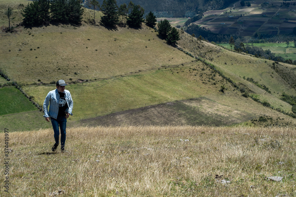 men climbing a big yellow mountain with a blue sky and green fields in the back ground