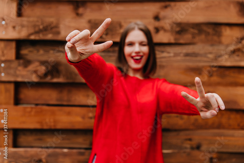 Pretty teen girl having fun. Outdoor photo of laughing young woman dancing on wooden background.