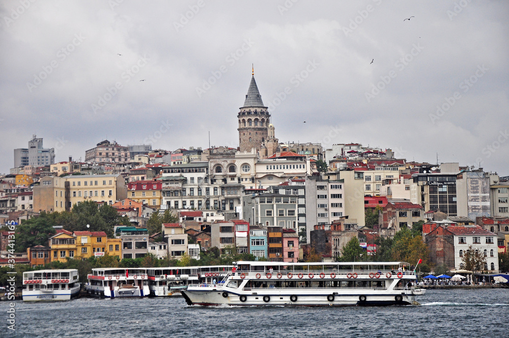 Istanbul's busy city scape and busy waterfron. The view includes the famous Galata Tower in the background. The tower is historic and has kept watch on the Bosphorus.